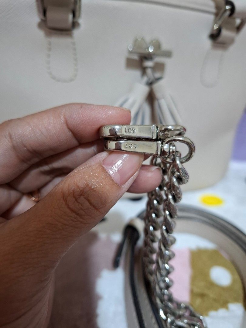 LOVCAT PARIS Handbag with Chain Strap [ORIGINAL] (Category: Luxury Bags & Wallets) located in Rizal. Submitted by she_prelovedbagsfromkorea (Listing ID 1409542418, Image 2). Description: - Cream-colored Lovcat handbag - Detachable chain strap - Top handle - Zip closure - Small interior pocket - Minor marks on exterior - Light tan interior lining - Tassel detail - Metal buckle with Lovcat brand name.