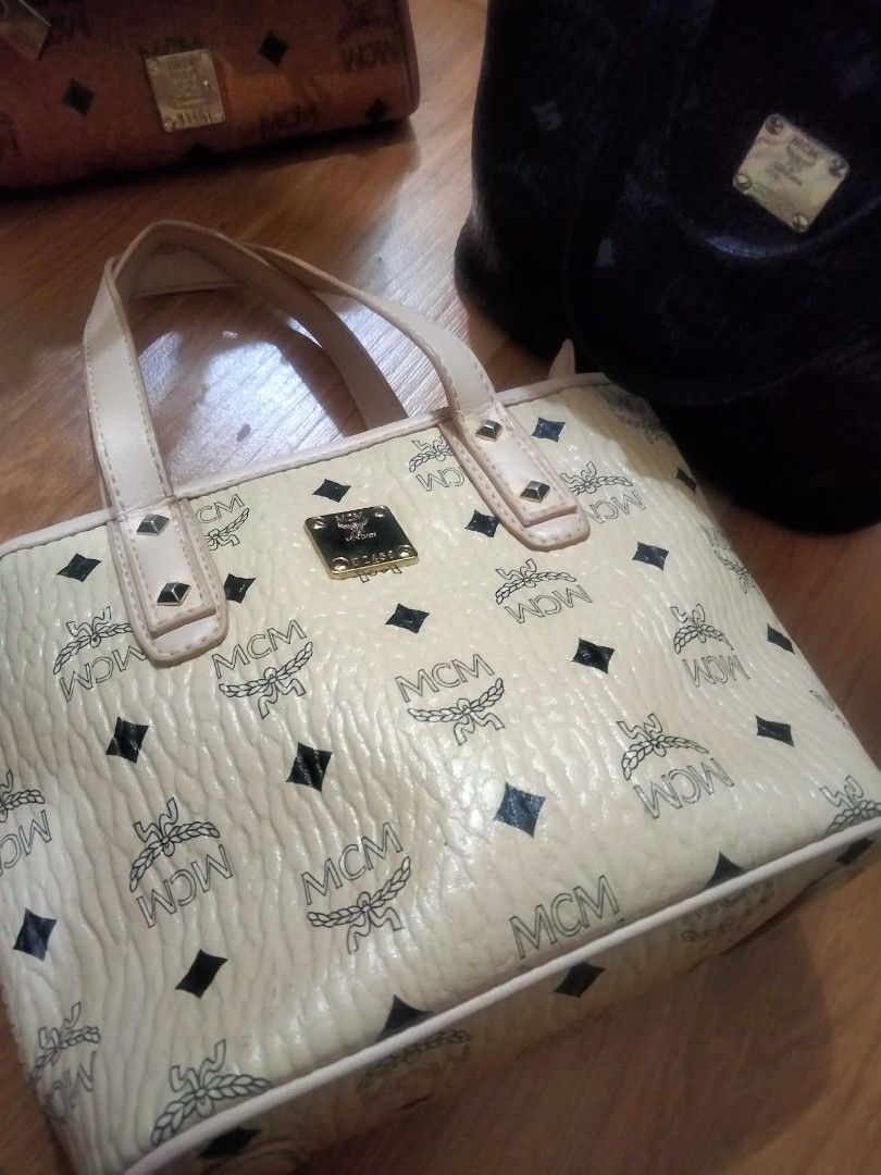 MCM Tote Bag (Category: Luxury Bags & Wallets) located in Cabanatuan. Submitted by almaespino24263 (Listing ID 1409503957, Image 1). Description: - Cream-colored MCM tote bag - Black diamond accents and MCM logos - Dual top handles - Gold-tone logo plaque - Made of textured material issues no sling straps .