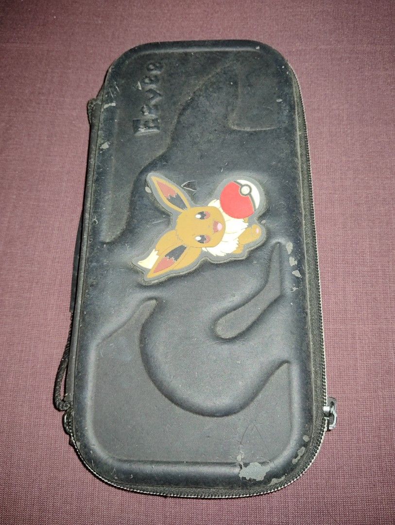 Pokemon Eevee Nintendo Switch Case (Category: Nintendo) located in Pasig City. Submitted by hazelscollectibles (Listing ID 1409468467, Image 2). Description: - Black Switch case see. pic for deets - Features an adorable Eevee design - Includes a convenient handle - Secure zipper closure - Internal slots for game cartridges - Mesh pocket for accessories - Designed to hold your Switch console and accessories.