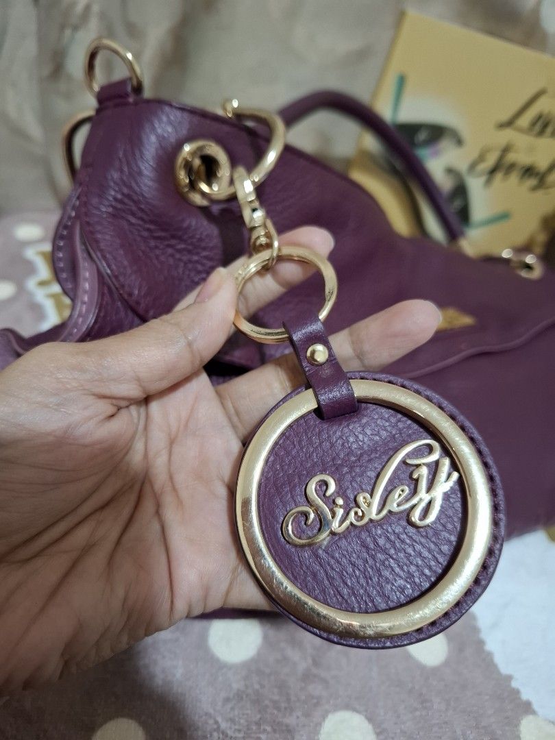 SISLEY Handbag - Purple [ORIGINAL] (Category: Luxury Bags & Wallets) located in Rizal. Submitted by she_prelovedbagsfromkorea (Listing ID 1409540831, Image 3). Description: - Authentic Sisley handbag - Stunning purple color - Elegant gold-tone hardware - Versatile top handle and detachable shoulder strap - Convenient interior zip pocket - Includes a stylish Sisley charm - Luxurious textured finish - Secure gold zipper - Interior lined with a patt