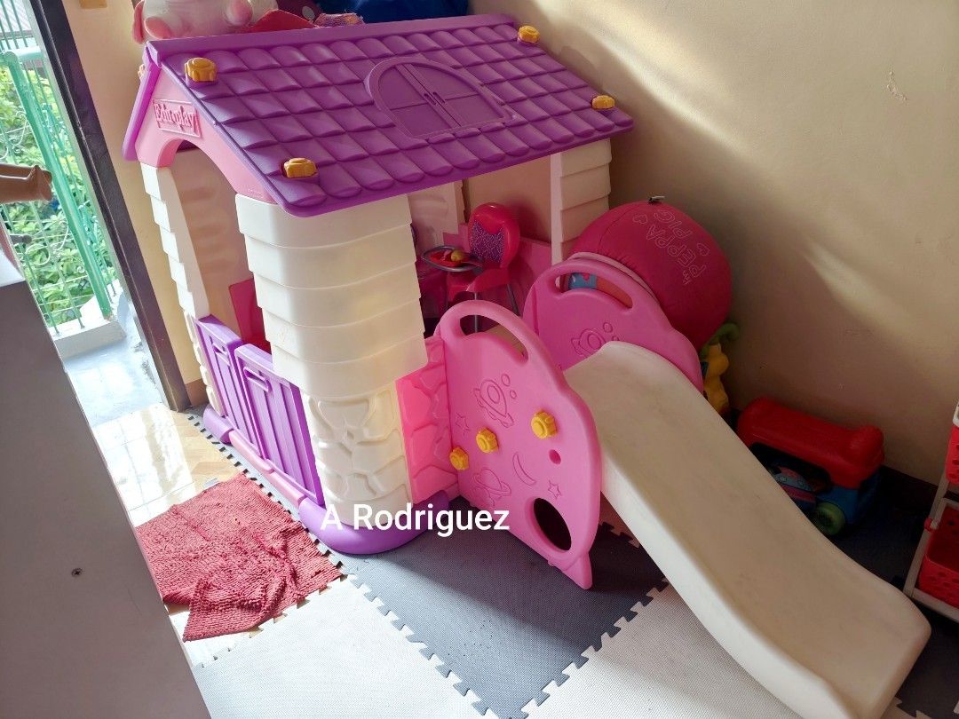 Eduplay Playhouse with Slide (Category: Infant Playtime) located in Manila. Submitted by declutterbabythings (Listing ID 1409758040, Image 2). Description: Eduplay playhouse features a slide and a small table with two chairs. The playhouse has a purple roof and door, with a white and purple body. The slide is pink and white. The playhouse is suitable for children..