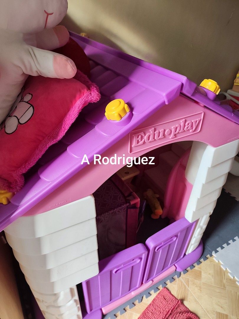 Eduplay Playhouse with Slide (Category: Infant Playtime) located in Manila. Submitted by declutterbabythings (Listing ID 1409758040, Image 3). Description: Eduplay playhouse features a slide and a small table with two chairs. The playhouse has a purple roof and door, with a white and purple body. The slide is pink and white. The playhouse is suitable for children..