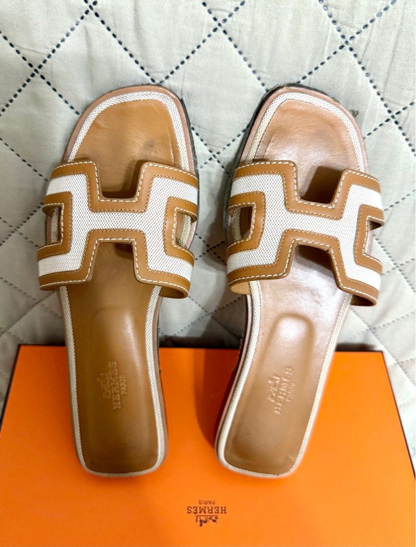Hermes Oran Sandals (Category: Sneakers & Footwear) located in Quezon City. Submitted by angeldana (Listing ID 1409758070, Image 1). Description: - Authentic Hermes Oran sandals - Tan leather footbed - White canvas strap - Signs of wear on the soles (with protective film (except some of the heels part; replacement of the protective film needed for a like-new look, or it can simply be removed). - Complete Inclusions (Box, paperbag, dustbags, ribbo