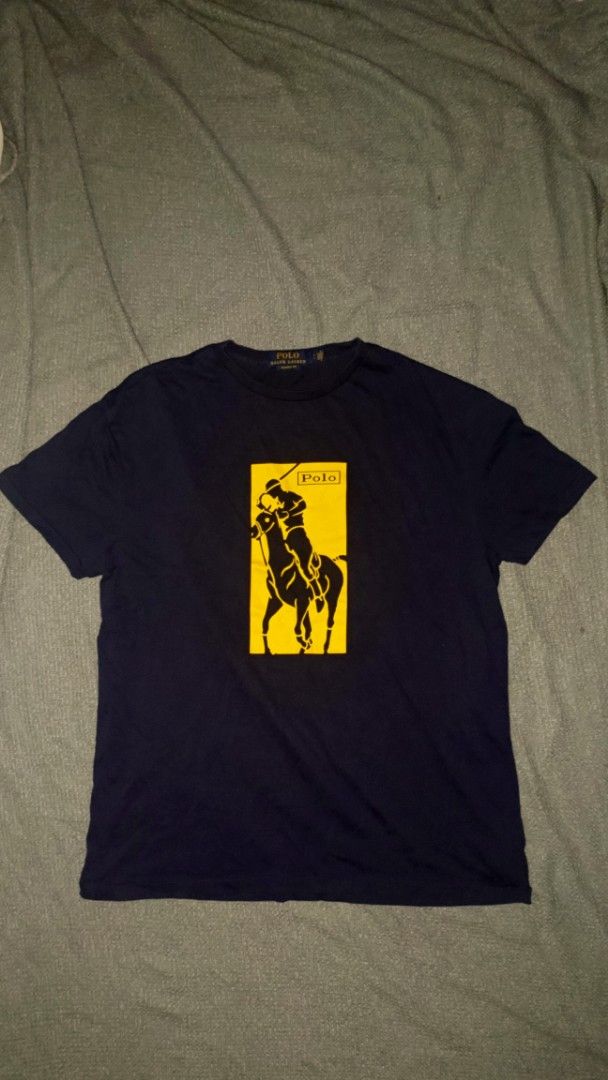 Polo Ralph Lauren T-shirt (Category: Tshirts & Polo Shirts ) located in Manila. Submitted by christ-chan (Listing ID 1409635735, Image 1). Description: - Navy blue Polo Ralph Lauren t-shirt - Features a yellow graphic of a polo player - Classic crew neck design - Short sleeves - Made of a soft material.