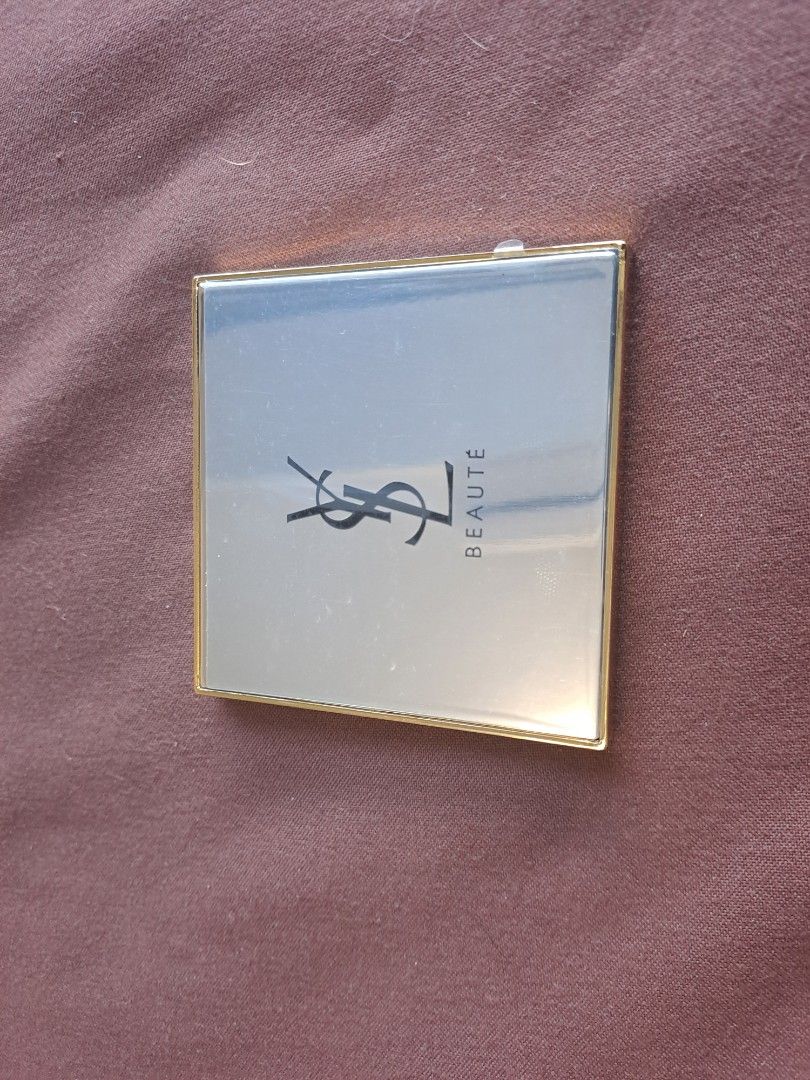 YSL Beauté Compact Mirror (Category: Mirrors) located in Manila. Submitted by joanbalde39643 (Listing ID 1409675221, Image 1). Description: - YSL Beauté compact mirror - Gold-colored frame - Features the YSL logo - Includes a black pouch with the YSL logo - Square-shaped.