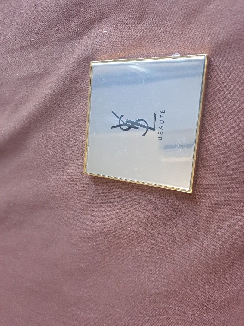 YSL Beauté Compact Mirror (Category: Mirrors) located in Manila. Submitted by joanbalde39643 (Listing ID 1409675221, Image 2). Description: - YSL Beauté compact mirror - Gold-colored frame - Features the YSL logo - Includes a black pouch with the YSL logo - Square-shaped.