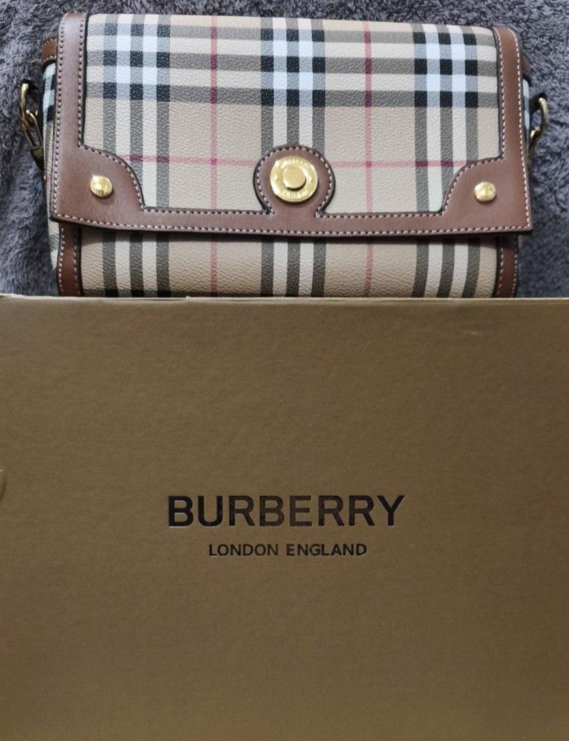 Super Sale!!! Burberry Note 2-Way Bag (Category: Luxury Bags & Wallets) located in Manila. Submitted by rjp25 (Listing ID 1409990786, Image 3). Description: - Beige strap with Burberry logo print - Brown leather ends - Gold-tone hardware - Includes two clasps for easy bag attachment - Stylish accessory.