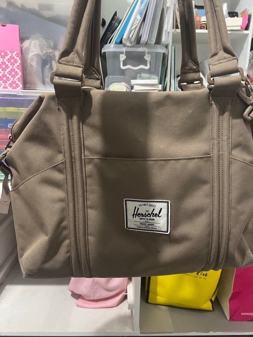 Herschel Supply Co. Tote Bag (Category: Tote Bags) located in Bocaue. Submitted by janishoppe (Listing ID 1409889411, Image 1). Description: - Herschel Supply Co. tote bag - Neutral brown color - Main compartment with red and white striped lining - Multiple interior pockets - Detachable shoulder strap - Top handles - Front pocket - Herschel Supply Co. logo patch.