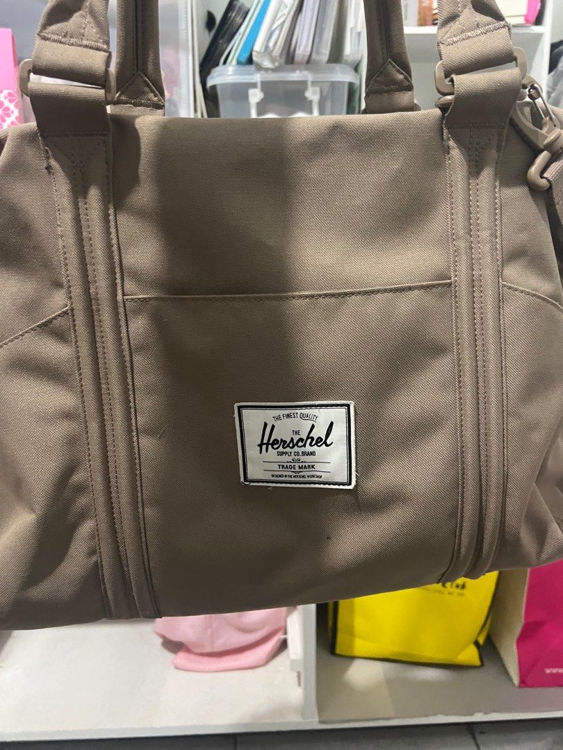 Herschel Supply Co. Tote Bag (Category: Tote Bags) located in Bocaue. Submitted by janishoppe (Listing ID 1409889411, Image 2). Description: - Herschel Supply Co. tote bag - Neutral brown color - Main compartment with red and white striped lining - Multiple interior pockets - Detachable shoulder strap - Top handles - Front pocket - Herschel Supply Co. logo patch.