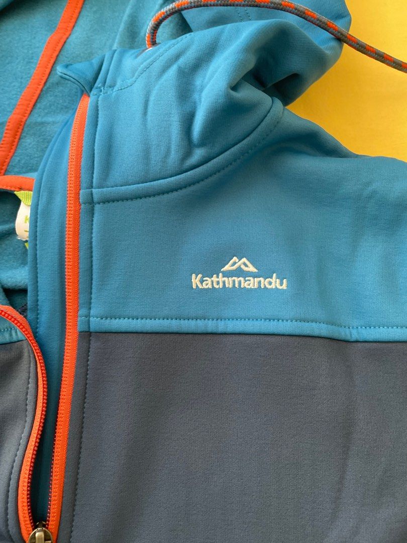 Kathmandu Hooded Jacket Size 14 (Category: Coats, Jackets and Outerwear) located in Manila. Submitted by winnieyols (Listing ID 1409863752, Image 2). Description: KATHMANDU ( NEW ZEALAND APPAREL BRAND ) - BRANDNEW / bought in NEW ZEALAND - ORIGINAL Kathmandu hooded jacket in blue and navy. SIZE : UK 14 Features a full zip closure, two front pockets, and a hood with a drawstring. The jacket has orange accents and the Kathmandu logo on the chest. -