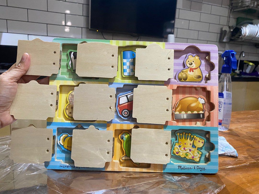 Melissa & Doug Wooden Hide & Seek Activity Board (Category: Educational & Learning Toys) located in Antipolo. Submitted by puzzleaddict (Listing ID 1409808957, Image 2). Description: Melissa & Doug activity board features hinged doors and magnetic puzzles. It includes various images like a barn, cookies, garage, and more. The board is designed for toddlers and kids. It is a preschool learning toy with nine wooden puzzles..