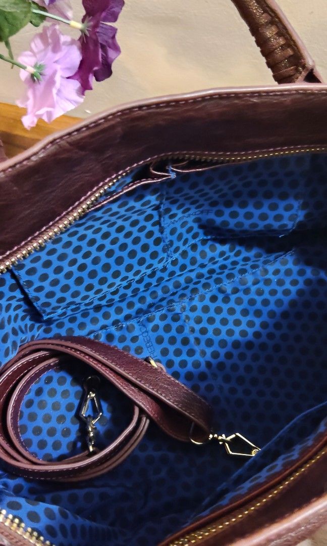 Rebecca Minkoff Handbag with Shoulder Strap (Category: Luxury Bags & Wallets) located in Davao. Submitted by nononbenjielunaivyibop (Listing ID 1395067232, Image 1). Description: - Rebecca Minkoff handbag -Satchel or tote style - Dark exterior with a shiny finish - Double handles and detachable shoulder strap - with intricate detailing and unique hardware - Interior with blue polka dot lining - Zipper closure - Includes a small charm.