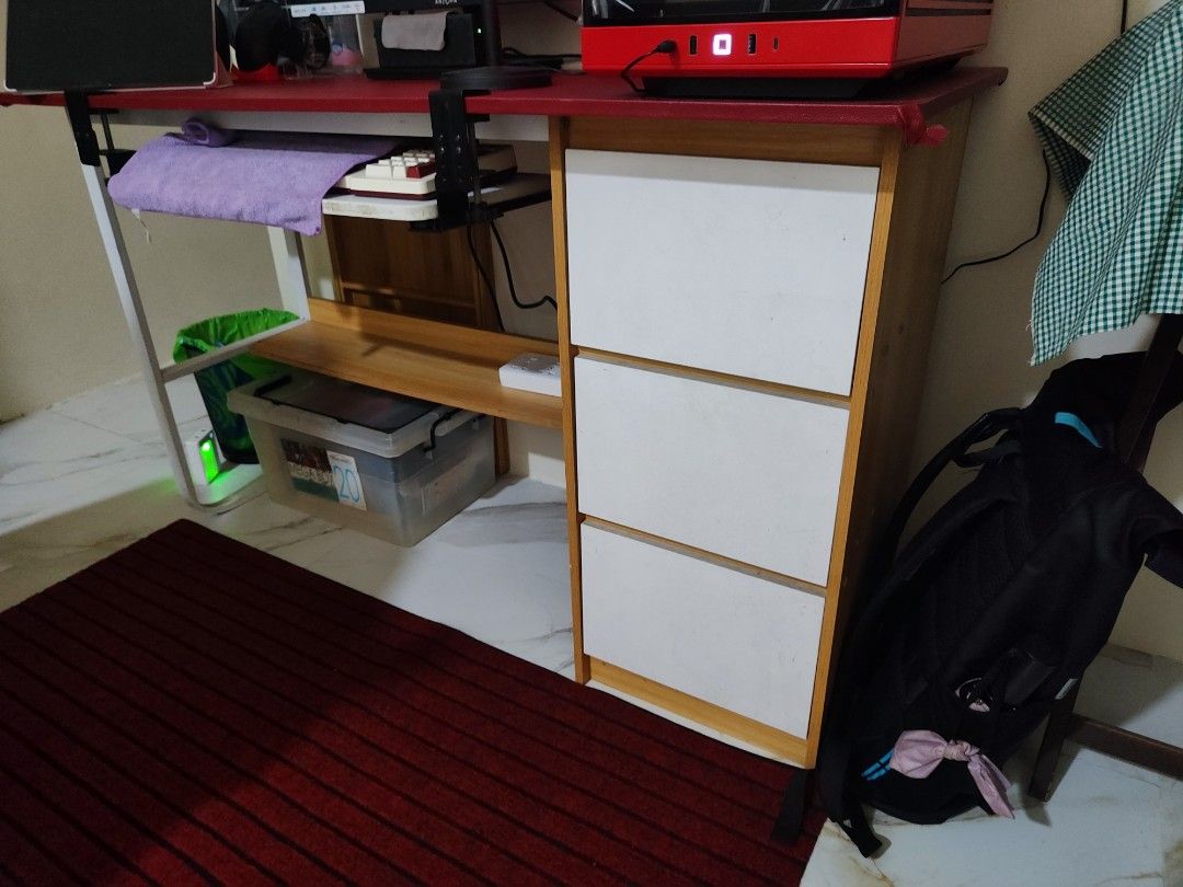 Wooden Desk with Red Tabletop Cover (Category: Tables & Sets) located in Marilao. Submitted by faeyie (Listing ID 1409963292, Image 2). Description: Disclaimer‼️Selling ONLY the table/desk. Other items in the picture are NOT FOR SALE. 🩷Red tabletop ( Can be removed. Orig tabletop color is wooden) 🩷With 3 drawers 🩷Wooden & Metal frame 🩷 Includes a bottom shelf 🩷 To be ship fully assembled so delivery via lalamove or grab is preferred.