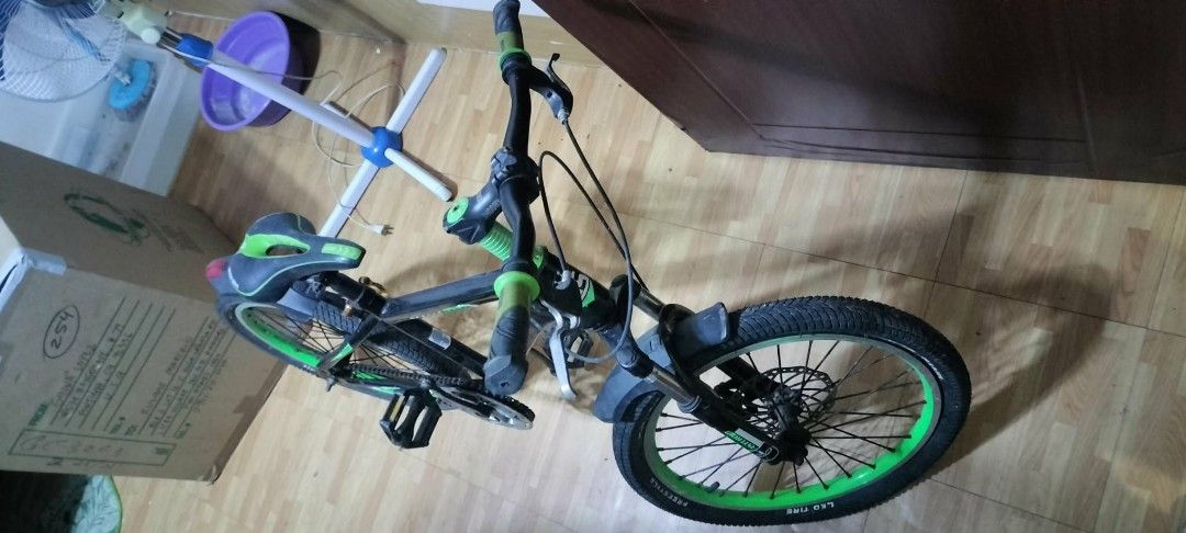 Black and Green Mountain Bike (Category: Bicycles) located in Rodriguez. Submitted by swiftwolf-dfd7eb (Listing ID 1410070340, Image 3). Description: This is a mountain bike, likely a 24 -inch size model. It features a full suspension design with front fork and rear frame suspension. The bike is equipped with disc brakes on both the front and rear wheels. It has a 21-speed gear system for varied terrain. The frame is black with distinct lime gree