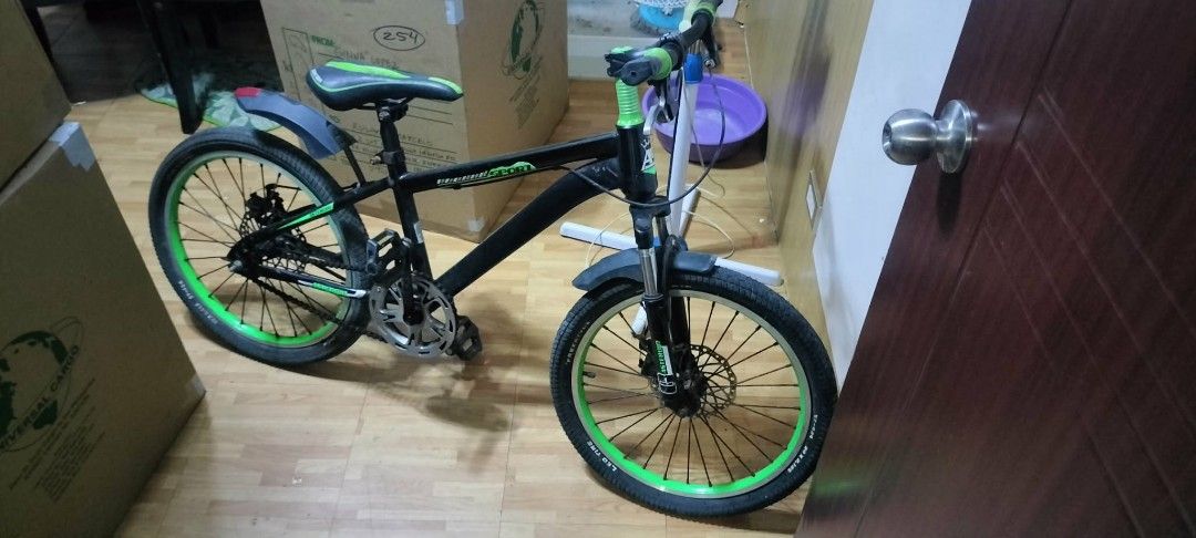 Black and Green Mountain Bike (Category: Bicycles) located in Rodriguez. Submitted by swiftwolf-dfd7eb (Listing ID 1410070340, Image 2). Description: This is a mountain bike, likely a 24 -inch size model. It features a full suspension design with front fork and rear frame suspension. The bike is equipped with disc brakes on both the front and rear wheels. It has a 21-speed gear system for varied terrain. The frame is black with distinct lime gree