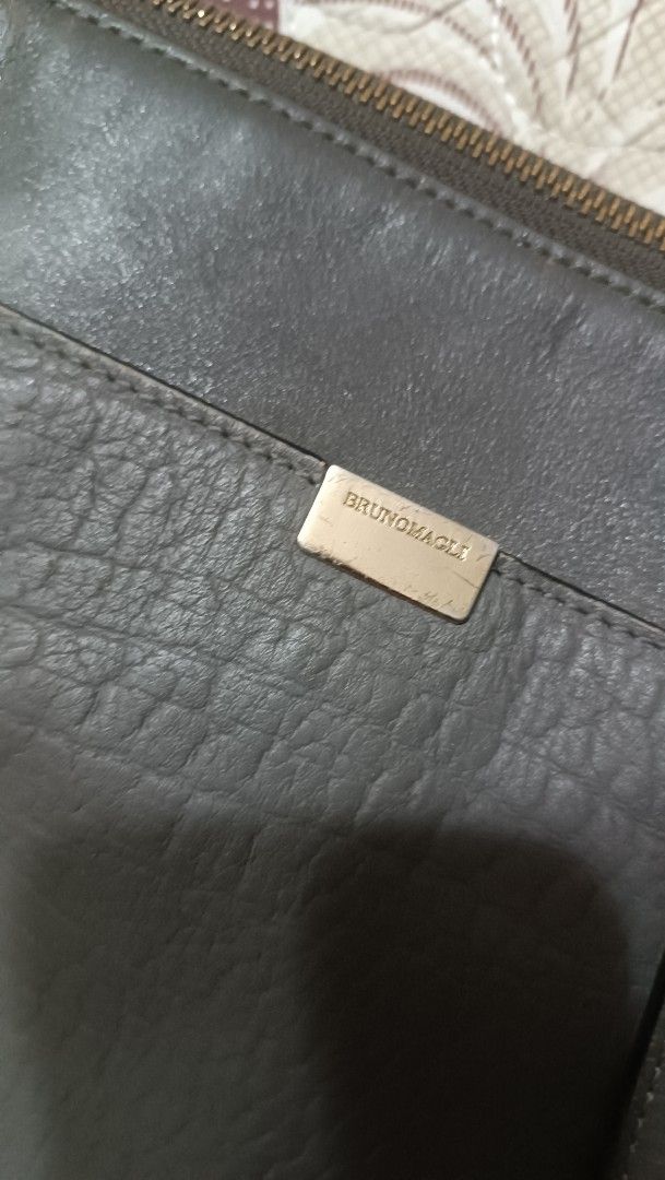 Bruno Magli Shoulder Bag (Category: Luxury Bags & Wallets) located in La Trinidad. Submitted by leezhine (Listing ID 1410152152, Image 3). Description: -Stylish Bruno Magli shoulder bag in a greyish color. - Features a textured genuine leather exterior with a top zipper closure. -The bag has a shoulder strap and a gold-toned metal accent with the brand name. -The interior is lined with a patterned fabric and includes multiple compartments for org