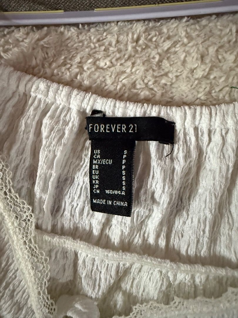 Forever 21 White Cami Top (Category: Sleeveless) located in Valenzuela. Submitted by raquesells (Listing ID 1410154449, Image 2). Description: - Forever 21 Cami Top - White color - Tie-front design - Delicate spaghetti straps - Textured fabric - Scalloped hemline - Lace trim on neckline and front - Perfect for a casual, feminine look.