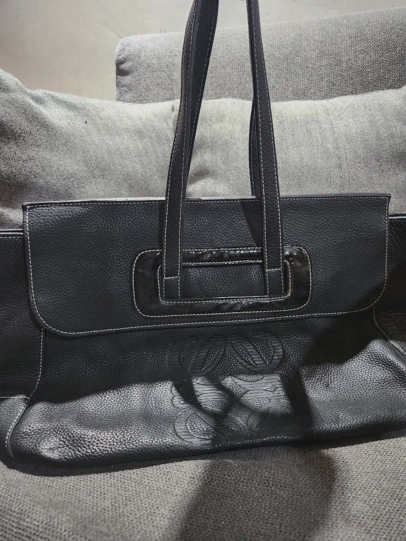 Loewe Black Leather Handbag (Category: Luxury Bags & Wallets) located in Cebu City. Submitted by atetskie (Listing ID 1410101391, Image 1). Description: Black leather handbag by Loewe. Features a top handle design with a flap closure. The interior is lined with fabric and includes a zipper pocket. The Loewe logo is visible on the interior lining and on a leather tag inside. The bag has a textured leather exterior and a decorative embossed design 