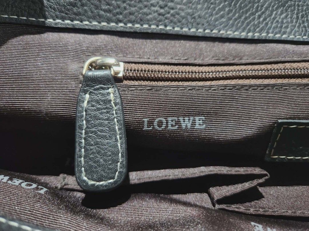 Loewe Black Leather Handbag (Category: Luxury Bags & Wallets) located in Cebu City. Submitted by atetskie (Listing ID 1410101391, Image 3). Description: Black leather handbag by Loewe. Features a top handle design with a flap closure. The interior is lined with fabric and includes a zipper pocket. The Loewe logo is visible on the interior lining and on a leather tag inside. The bag has a textured leather exterior and a decorative embossed design 