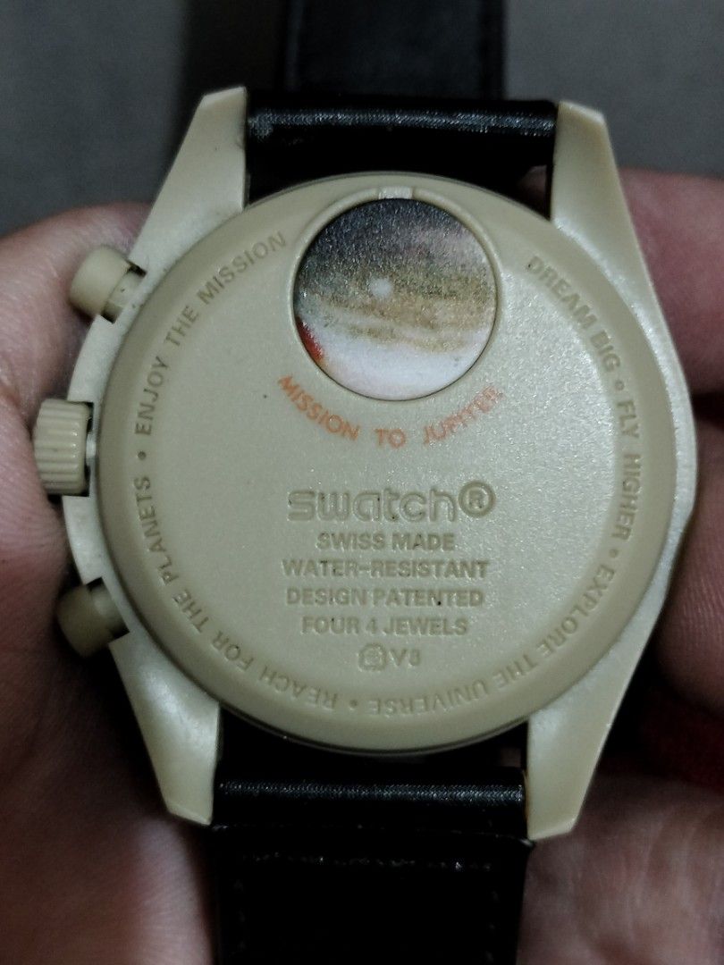 Omega x Swatch Speedmaster Mission to Jupiter (Category: Luxury Watches) located in Santa Rosa. Submitted by ericilagan822.1 (Listing ID 1410041680, Image 2). Description: Watch features a cream-colored dial with chronograph subdials and a tachymeter bezel. The black strap is branded with "Speedmaster Moon's Watch" and "Omega" logos. The case back is marked "Mission to Jupiter" and "Swatch Swiss Made". The watch is water-resistant and has a desig