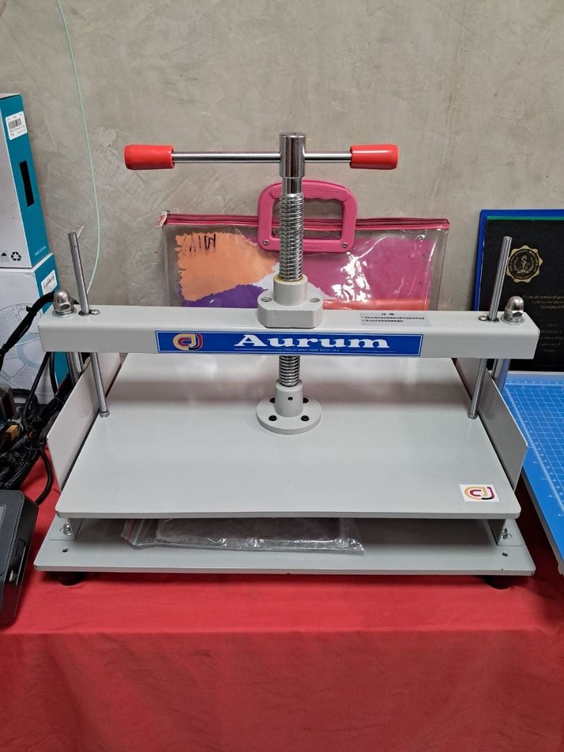 Aurum Press Machine A3 (Category: Craft Supplies & Tools) located in Quezon City. Submitted by copieronlineinc (Listing ID 1410198966, Image 2). Description: Sturdy Aurum book press. It features a screw mechanism for applying pressure. The press has a large base and a handle for easy operation. The press is painted in a light grey color..