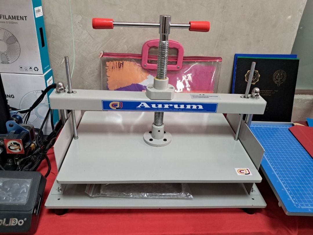 Aurum Press Machine A3 (Category: Craft Supplies & Tools) located in Quezon City. Submitted by copieronlineinc (Listing ID 1410198966, Image 1). Description: Sturdy Aurum book press. It features a screw mechanism for applying pressure. The press has a large base and a handle for easy operation. The press is painted in a light grey color..
