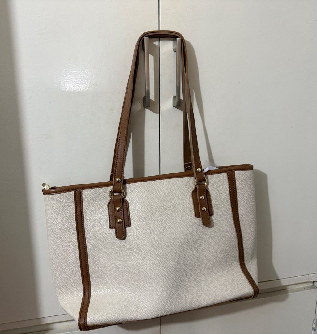 Jovanni Shoulder Bag (Brand New) (Category: Tote Bags) located in Caloocan City. Submitted by joycemiramar (Listing ID 1410208379, Image 2). Description: - ZMNNE tote bag in white with brown trim and handles. - Zippered main compartment. - Interior pockets for organization. - Structured, rectangular design. - Gold-colored hardware. - Includes a tag..