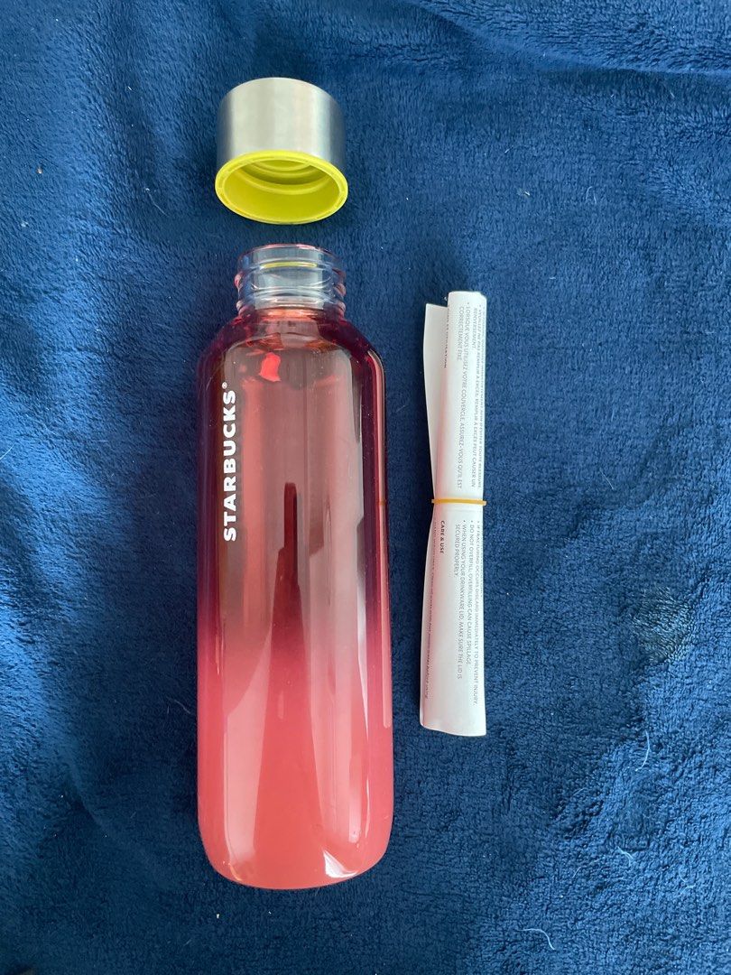 Starbucks Water Bottle 20oz (Category: Water Bottles & Tumblers) located in Taguig. Submitted by fae99 (Listing ID 1410231736, Image 2). Description: - Brand New, never used - Purchased in US $22.95 - Starbucks water bottle features a red gradient design. It has a silver cap with a yellow ring and a clear body. The bottle includes a paper insert. The bottom of the bottle has a sticker with the Starbucks logo and product information. It is made in