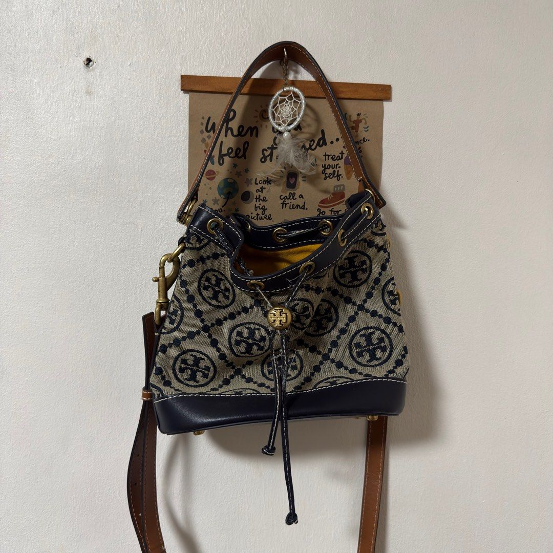 Tory Burch Monogram Jacquard Mini Bucket Bag (Category: Luxury Bags & Wallets) located in Bacoor. Submitted by pausroom (Listing ID 1410336546, Image 1). Description: - Tory Burch bucket bag - Navy and beige pattern - Drawstring closure - Leather base and trim - Detachable shoulder strap - Yellow interior - Gold-tone logo and hardware - Small pocket on the back - LP posted - Orig price 1500 Only flaw is the string not guaranteed auth RFS: declutt