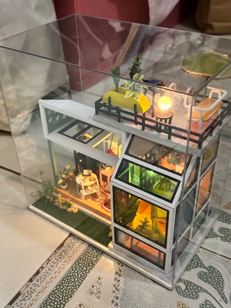 DIY Miniature Dollhouse with LED Lights (Category: Kids Toys) located in Manila. Submitted by judeo. (Listing ID 1410486293, Image 1). Description: Already build miniature!!❤️ - Modern miniature dollhouse - Features multiple rooms and a rooftop patio - Includes detailed furniture and plants - Comes with LED lighting - Enclosed in a clear display case - Perfect for collectors and decoration.