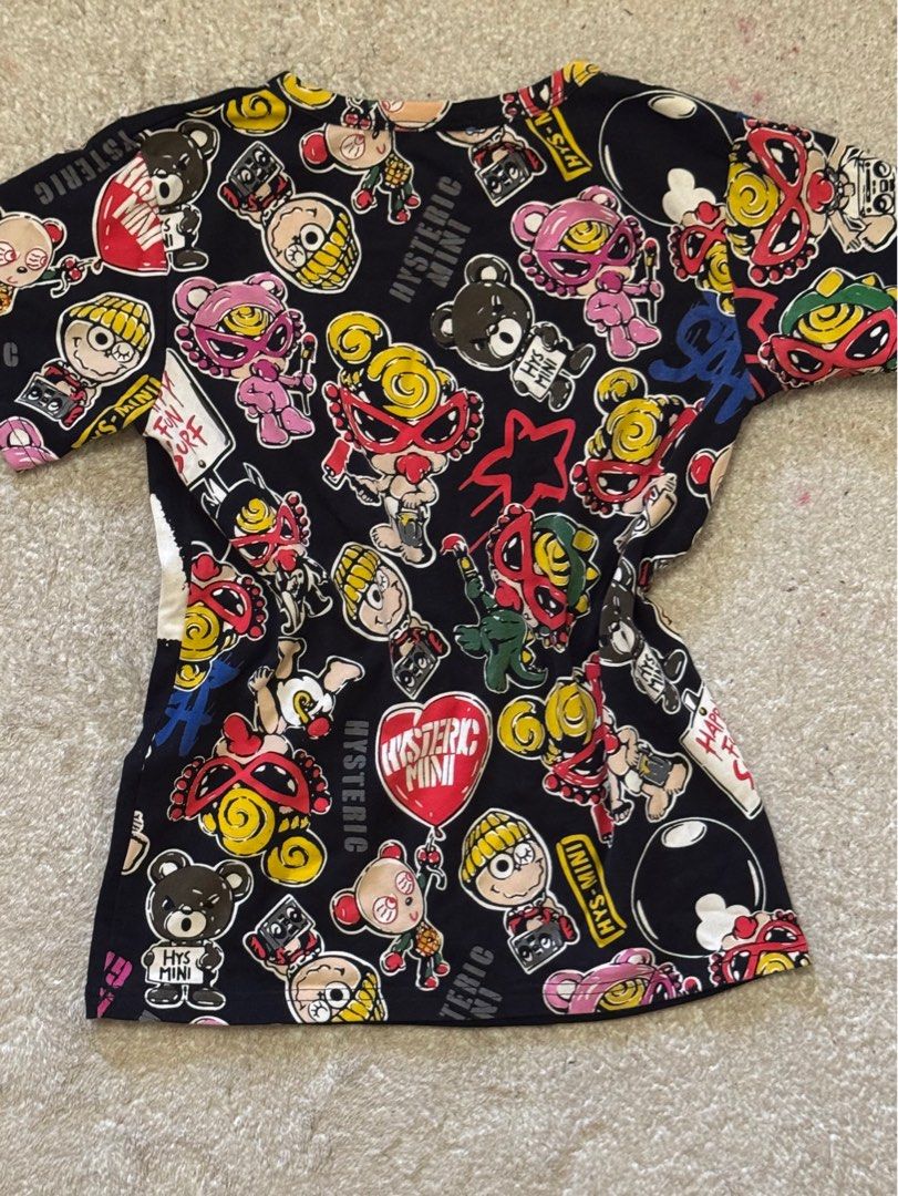 Hysteric Glamour Graphic Tee (Category: Tshirts & Polo Shirts ) located in Paranaque City. Submitted by passion_pluto (Listing ID 1410419726, Image 3). Description: - Black Hysteric Glamour graphic tee - Features a unique cartoon character design - Design includes a character with yellow hair and a red mask - Short sleeves and a classic crew neck - Sleeves adorned with cartoon character pattern - Brand name prominently displayed on the collar.