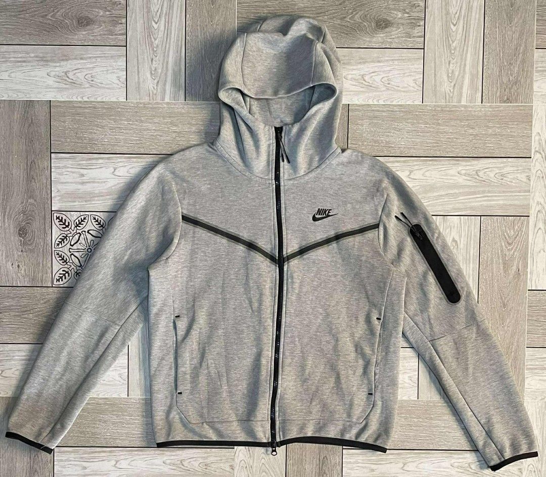 Nike Tech Fleece Hoodie Jacket (Category: Coats, Jackets and Outerwear) located in Caloocan City. Submitted by sneakcity_ (Listing ID 1410410341, Image 1). Description: - Nike Tech Fleece hoodie jacket - Gray color - Black stripe design across the chest - Full zip closure - Hooded - Zippered pocket on left sleeve - Small Nike logo Condition: 9.5/10 Color Rate: 10/10 Size On Tag: XL(fits Medium) Dimensions: Width - 23 Length - 26.5 Sleeves Length 