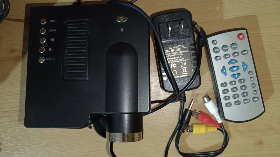 Portable Projector with Remote (Category: Projectors) located in Valenzuela. Submitted by just_m33 (Listing ID 1410437002, Image 2). Description: UNIC UC28 MINI PROJECTOR Portable projector comes with a remote control, power adapter, and AV cables. It features USB, AV-in, SD card slot, VGA, and HDMI ports. The projector displays options for movie, photo, text, and music. It has a 12V DC, 2A power input and uses an LCD image unit with LED lamp. *N