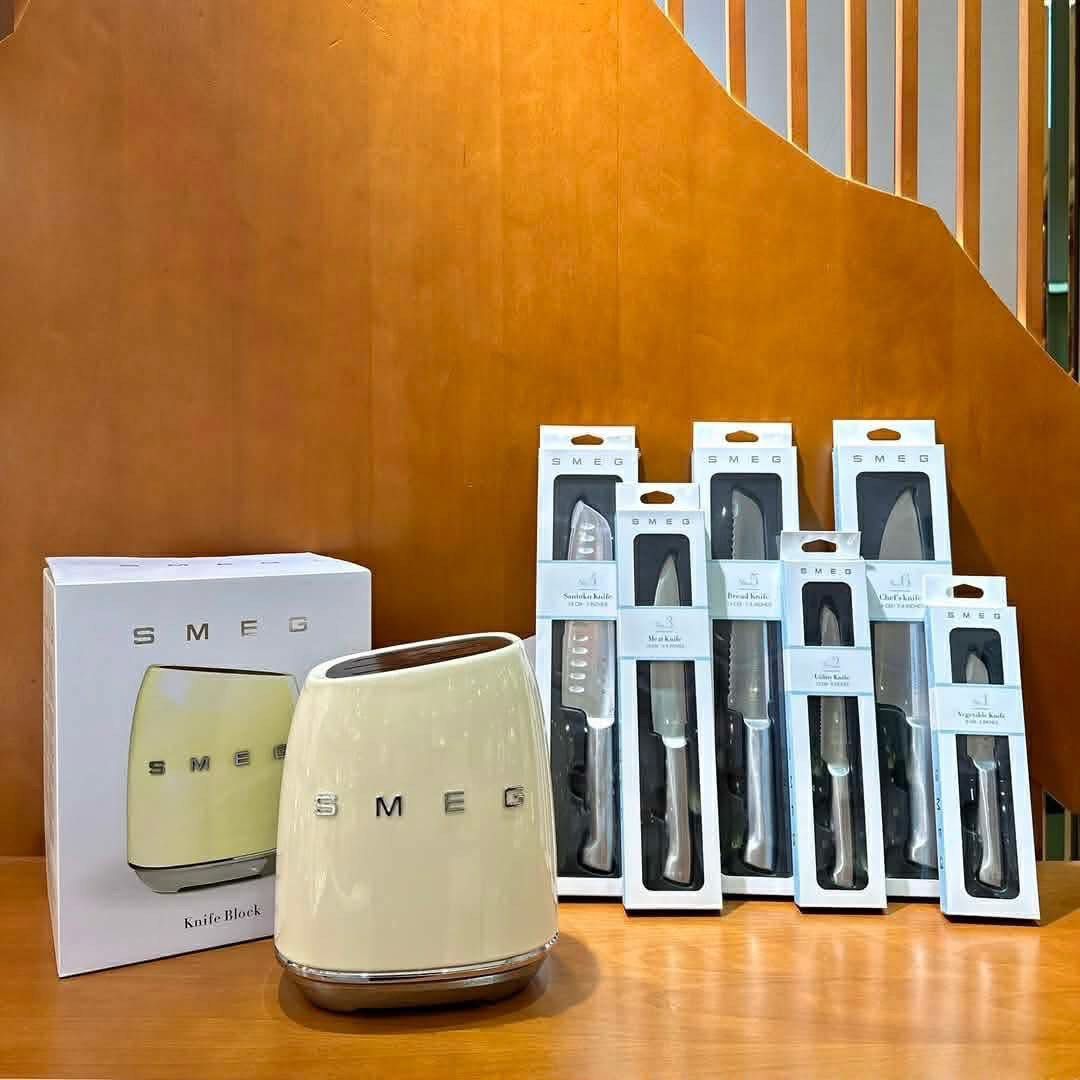 Smeg Knife Block Set (Category: Knives & Chopping Boards) located in Manila. Submitted by beaumontandco (Listing ID 1410508531, Image 1). Description: - Smeg knife block set. - Includes a cream-colored knife block with the Smeg logo. - Knives made of German steel 1.4116. - Set includes various knives for different purposes..