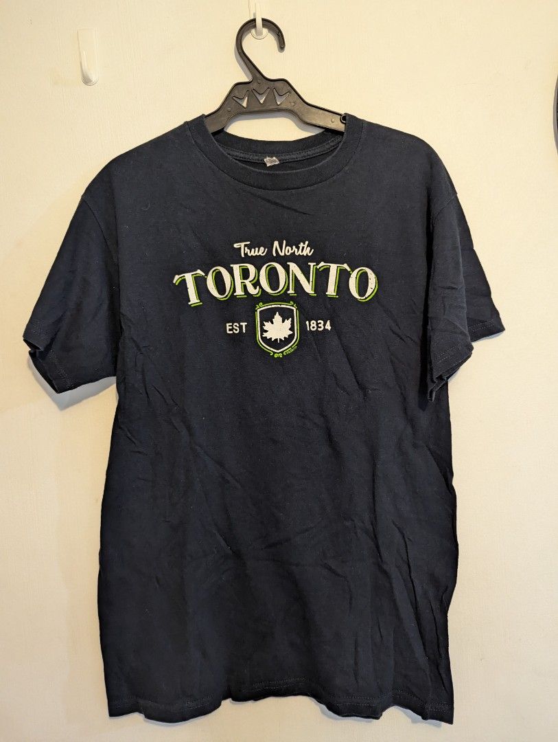 Toronto True North T-shirt (Category: Tshirts & Polo Shirts ) located in Porac. Submitted by themightythrift (Listing ID 1410630760, Image 1). Description: - Dark blue Toronto True North T-shirt - Features Toronto logo with maple leaf emblem and 1834 - Short sleeves - Crew neck - Soft fabric - Plain back.