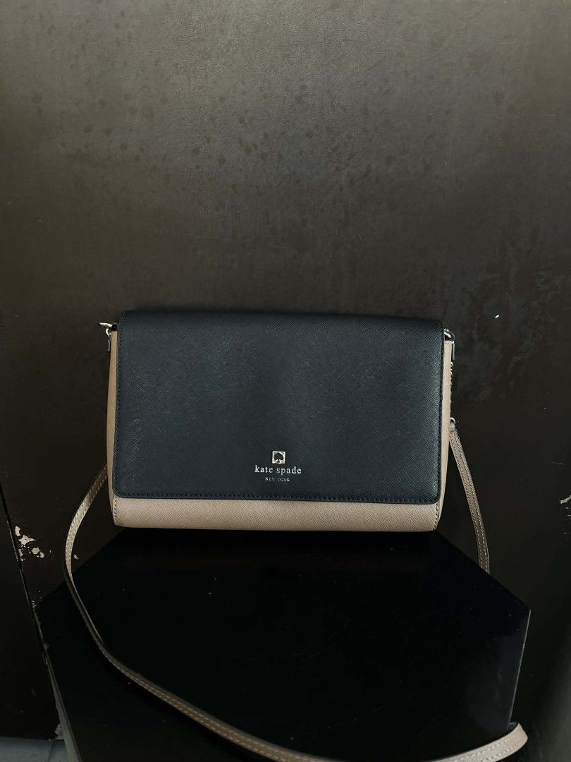 Kate Spade Two-Tone Crossbody Bag (Category: Cross-body Bags) located in Quezon City. Submitted by peralnorie53313 (Listing ID 1407395324, Image 1). Description: Kate Spade crossbody bag in a two-tone design. Features a navy blue flap and a tan body. Includes a chain strap and a Kate Spade logo on the front. The interior has a fabric lining with the Kate Spade logo pattern. The bag has a small stain on the side. Made in China,minimal fade on logo