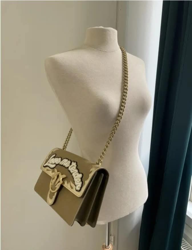 Pinko Love Me Tender Messenger Bag (Category: Luxury Bags & Wallets) located in Villasis. Submitted by mysticforest.bb2b4b (Listing ID 1407399962, Image 3). Description: - Pinko Love Me Tender messenger bag - Color: Olive Green - Gold chain strap - Signature Love Birds buckle - Flap closure - Interior pocket - Exterior detail: "Love Me Tender".