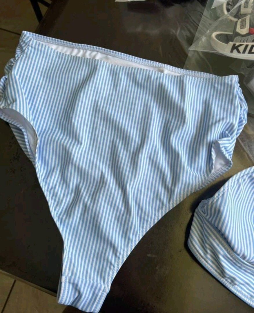 Shein Striped High Waist Bikini Set (Category: Bikinis & Swimsuits) located in Manila. Submitted by monaaa03 (Listing ID 1407558344, Image 3). Description: Light blue and white striped bikini set from Shein. Features a triangle top and high-waisted bottoms. The bottoms have a ruched detail on the sides. Perfect for the beach or pool..