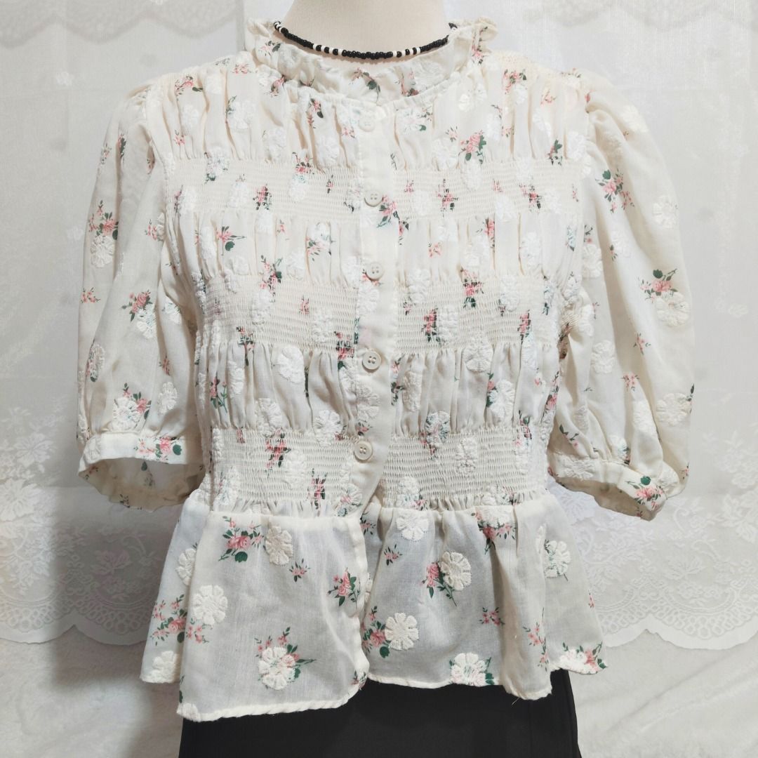 Cream Smocked Floral Button Down Peplum Blouse (Category: Blouses) located in Mandaluyong City. Submitted by princesspockets (Listing ID 1410861479, Image 3). Description: Premium top! The bodice has multiple smocking and working buttons. Features a ruffled mock neck and puff sleeves. Best fit: M-XL 🌸 FLAT LAY MEASUREMENTS 🌸 Bust: 32-40 in Length: 20 in 🌸 REMINDERS 🌸 - Thrifted / Preloved / Ukay, lightly washed. PLEASE MANAGE YOUR EXPECTATION