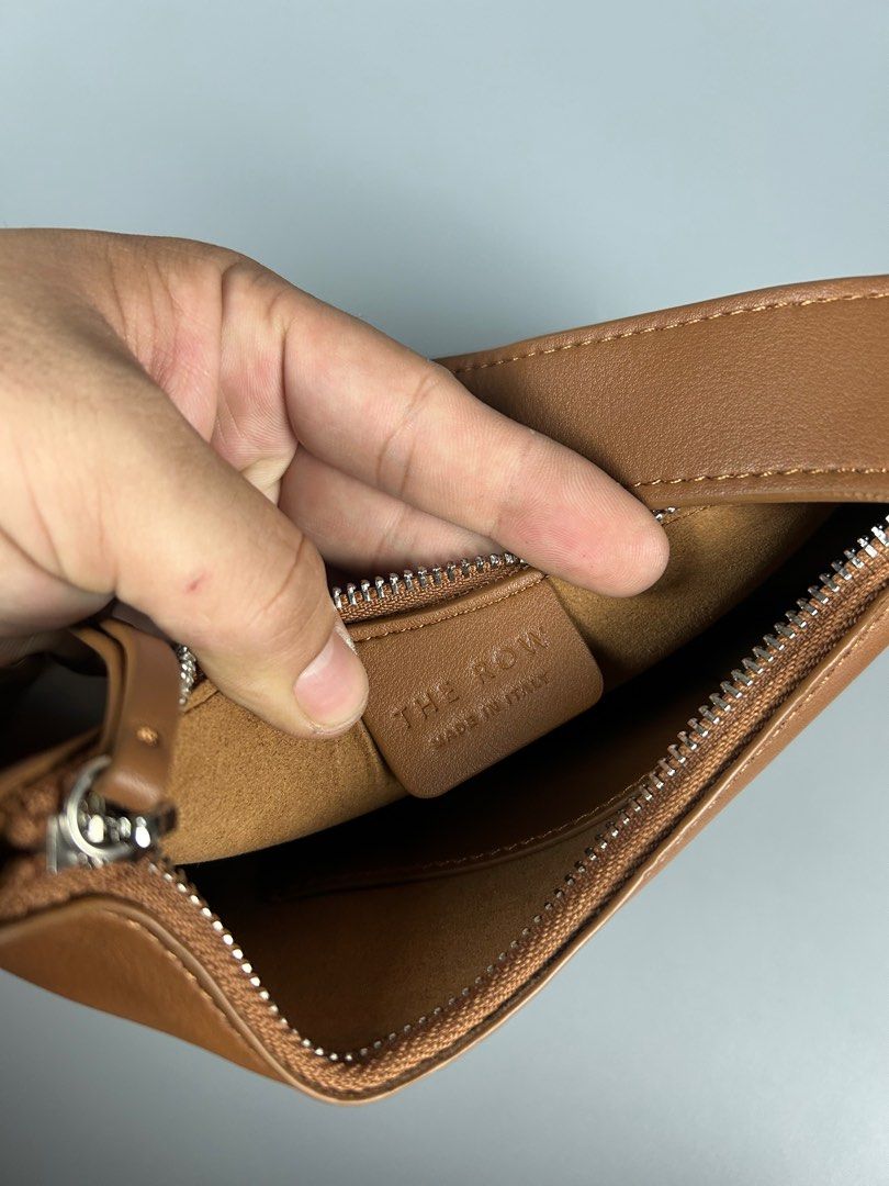 The Row Half-moon Bag (Category: Luxury Bags & Wallets) located in Manila. Submitted by 3rdealz (Listing ID 1410803174, Image 3). Description: - The Row shoulder bag in brown. - Curved design with a single shoulder strap. - Features a zipper closure. - Interior: Branded tag "The Row Made in Italy". - Condition: Minor wear and tear..