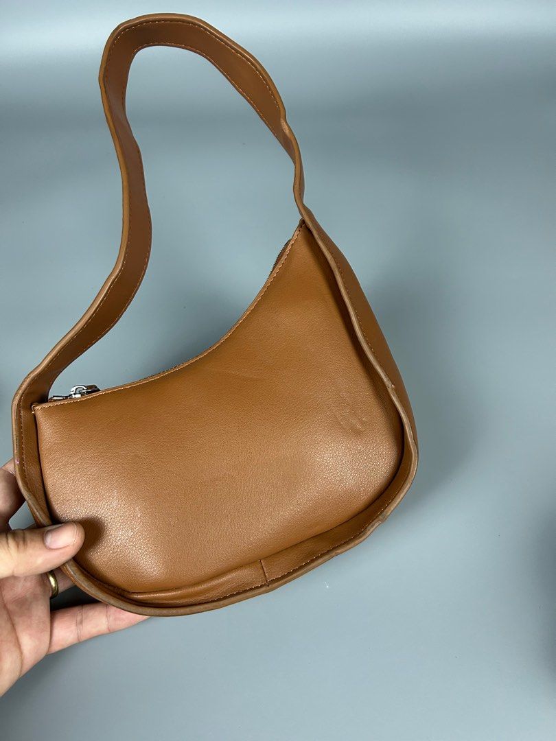 The Row Half-moon Bag (Category: Luxury Bags & Wallets) located in Manila. Submitted by 3rdealz (Listing ID 1410803174, Image 2). Description: - The Row shoulder bag in brown. - Curved design with a single shoulder strap. - Features a zipper closure. - Interior: Branded tag "The Row Made in Italy". - Condition: Minor wear and tear..