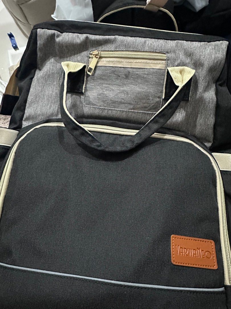 Varwaneo Diaper Bag with Bassinet (Category: Diaper Bags & Wetbags) located in Porac. Submitted by prelovedclothing29 (Listing ID 1410731351, Image 3). Description: used once - Varwaneo diaper bag with built-in bassinet for easy on-the-go changes. - Features multiple compartments and pockets for organizing baby essentials. - Stylish black design with gray accents and tan trim. - Includes a clear front pocket for easy access. - Comfortable handle 