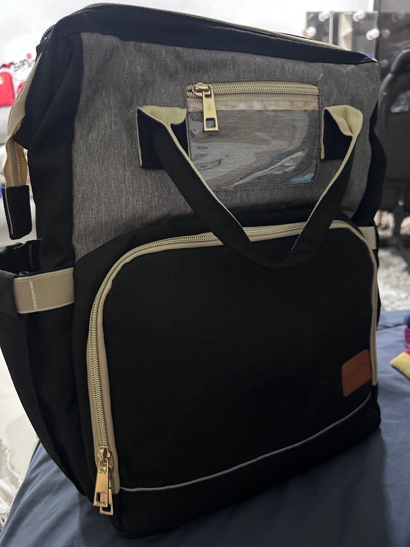 Varwaneo Diaper Bag with Bassinet (Category: Diaper Bags & Wetbags) located in Porac. Submitted by prelovedclothing29 (Listing ID 1410731351, Image 2). Description: used once - Varwaneo diaper bag with built-in bassinet for easy on-the-go changes. - Features multiple compartments and pockets for organizing baby essentials. - Stylish black design with gray accents and tan trim. - Includes a clear front pocket for easy access. - Comfortable handle 