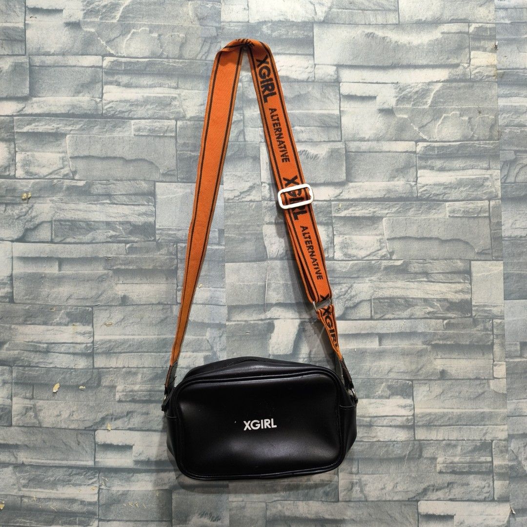 XGirl Black Shoulder Bag (Category: Sling Bags) located in Manila. Submitted by tapsilooog (Listing ID 1410886683, Image 1). Description: - X-Girl black shoulder bag - Adjustable orange strap with X-Girl logo - Rectangular shape - X-Girl logo on front - Smooth, possibly leather-like material - Adjustable buckle on strap RFS DECLUTTERING .
