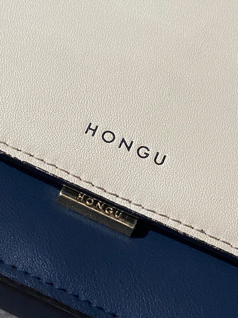 Hongu Two-Tone Shoulder Bag (Category: Luxury Bags & Wallets) located in Manila. Submitted by _rieliez (Listing ID 1410902645, Image 2). Description: - Hongu shoulder bag - Two-tone design: cream and navy blue - Chain strap with scarf detail - Additional navy blue strap - Rectangular shape - Flap closure - Single compartment - Interior zipper pocket ISSUES: stain inside the compartment strap is a little worn out.