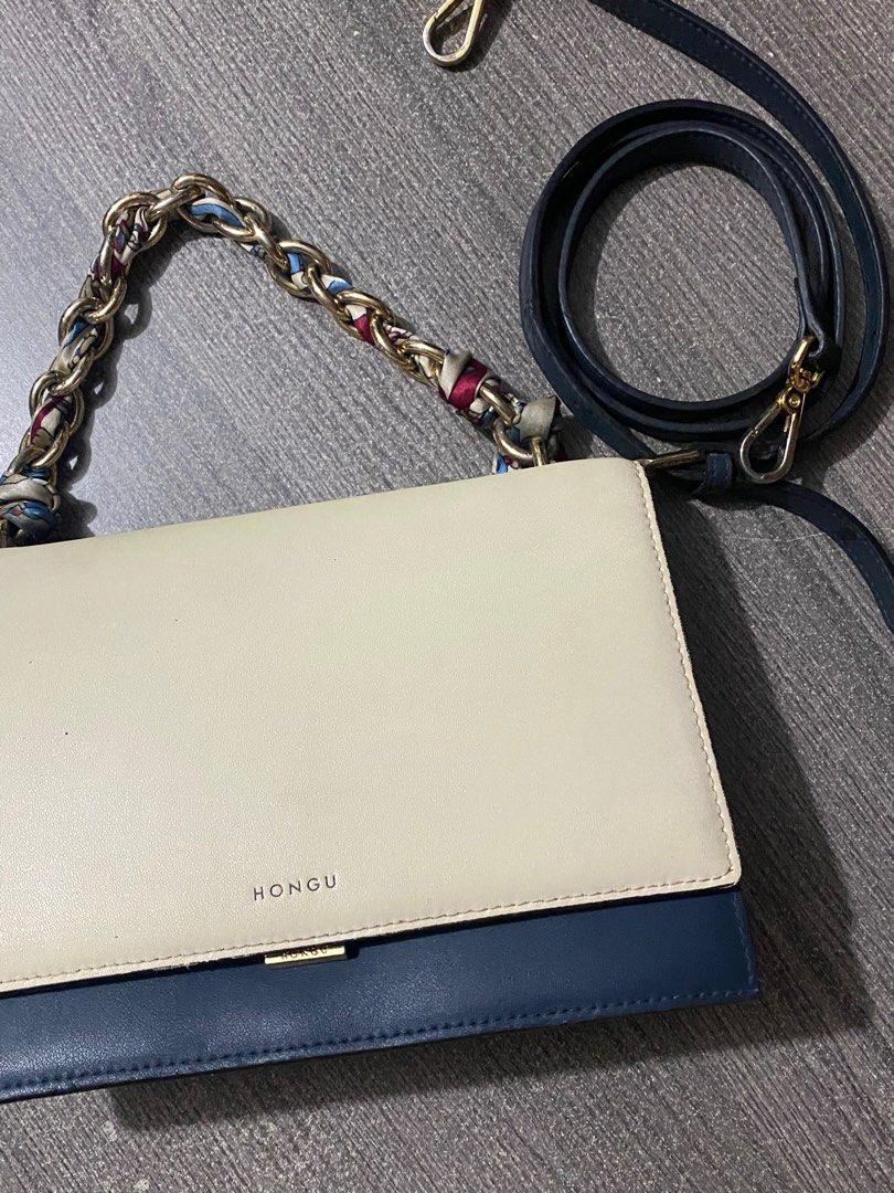 Hongu Two-Tone Shoulder Bag (Category: Luxury Bags & Wallets) located in Manila. Submitted by _rieliez (Listing ID 1410902645, Image 1). Description: - Hongu shoulder bag - Two-tone design: cream and navy blue - Chain strap with scarf detail - Additional navy blue strap - Rectangular shape - Flap closure - Single compartment - Interior zipper pocket ISSUES: stain inside the compartment strap is a little worn out.
