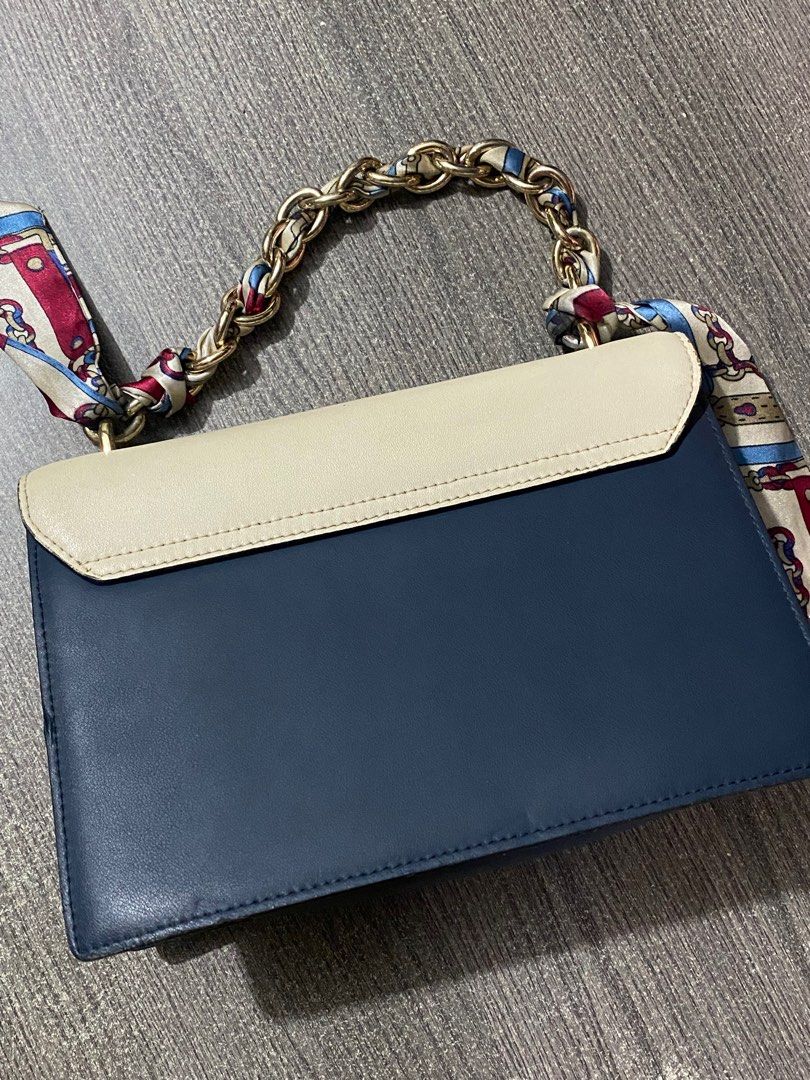 Hongu Two-Tone Shoulder Bag (Category: Luxury Bags & Wallets) located in Manila. Submitted by _rieliez (Listing ID 1410902645, Image 3). Description: - Hongu shoulder bag - Two-tone design: cream and navy blue - Chain strap with scarf detail - Additional navy blue strap - Rectangular shape - Flap closure - Single compartment - Interior zipper pocket ISSUES: stain inside the compartment strap is a little worn out.