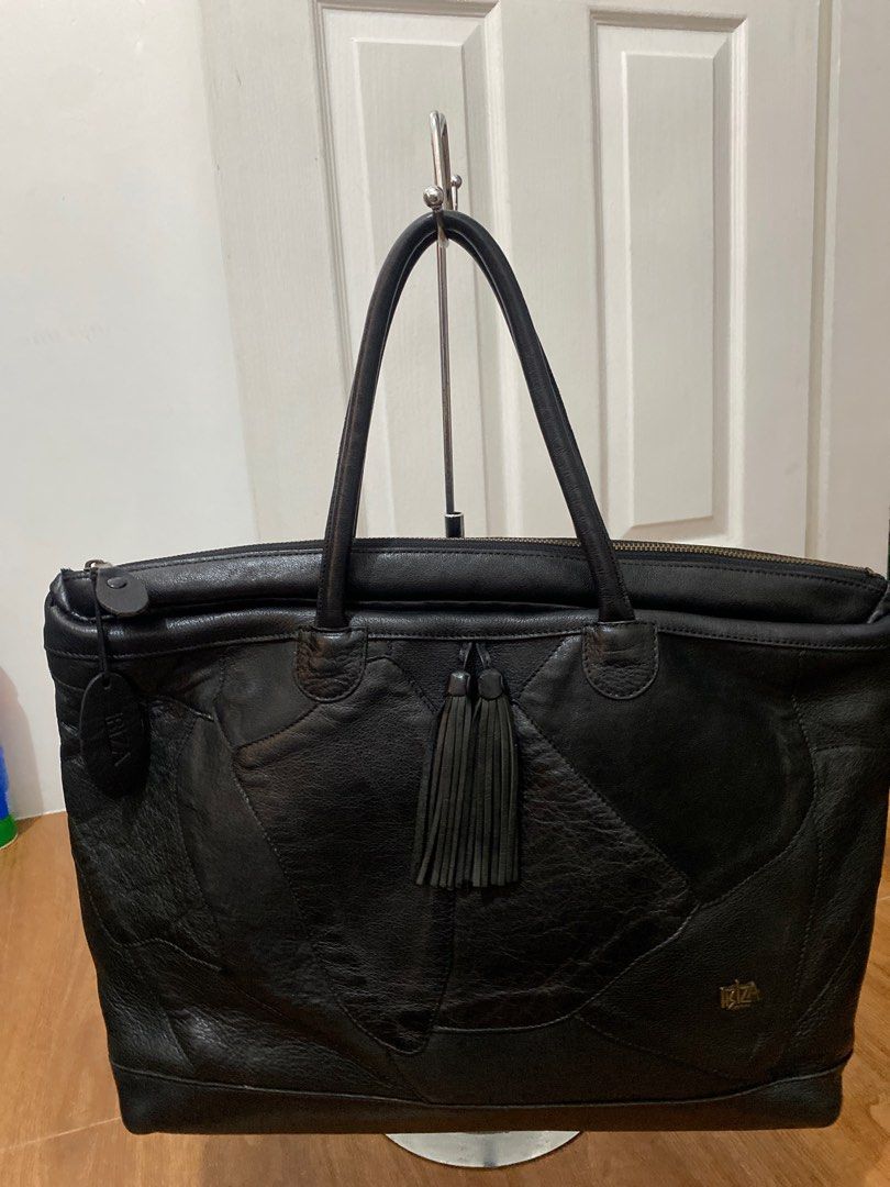 Ibiza Genuine Leather Tote Bag (Category: Tote Bags) located in Quezon City. Submitted by modificabagsph (Listing ID 1410950990, Image 1). Description: Black leather tote bag from Ibiza. Features a zip closure, dual top handles, and decorative tassels. Includes an interior zip pocket and multiple compartments. The bag has a patch design and a metal Ibiza logo. The interior lining is black. The bag has a tag with the Ibiza logo..