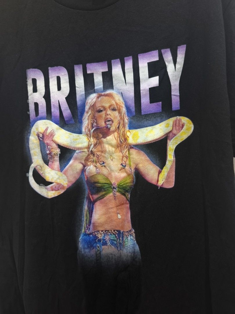 Britney Spears Black Graphic Tee (Category: Tshirts & Polo Shirts ) located in Manila. Submitted by nmictbon40960 (Listing ID 1411122653, Image 2). Description: - Britney Spears graphic t-shirt - Features a graphic of Britney Spears with a snake - "Britney" printed above the image in purple and white - Standard crew neck style - Graphic centered on the front.