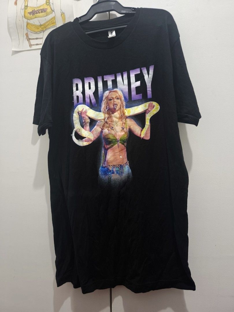 Britney Spears Black Graphic Tee (Category: Tshirts & Polo Shirts ) located in Manila. Submitted by nmictbon40960 (Listing ID 1411122653, Image 1). Description: - Britney Spears graphic t-shirt - Features a graphic of Britney Spears with a snake - "Britney" printed above the image in purple and white - Standard crew neck style - Graphic centered on the front.